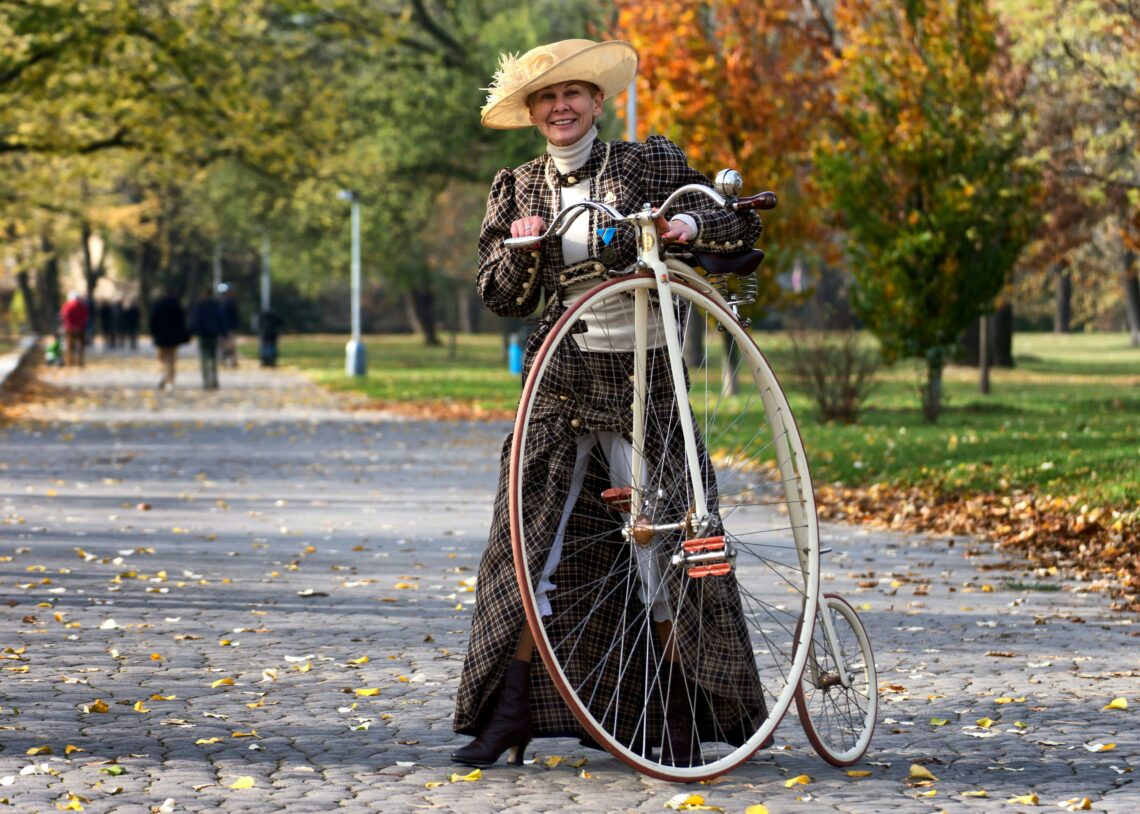 A lady in old-fashioned clothing next to a penny-farthing